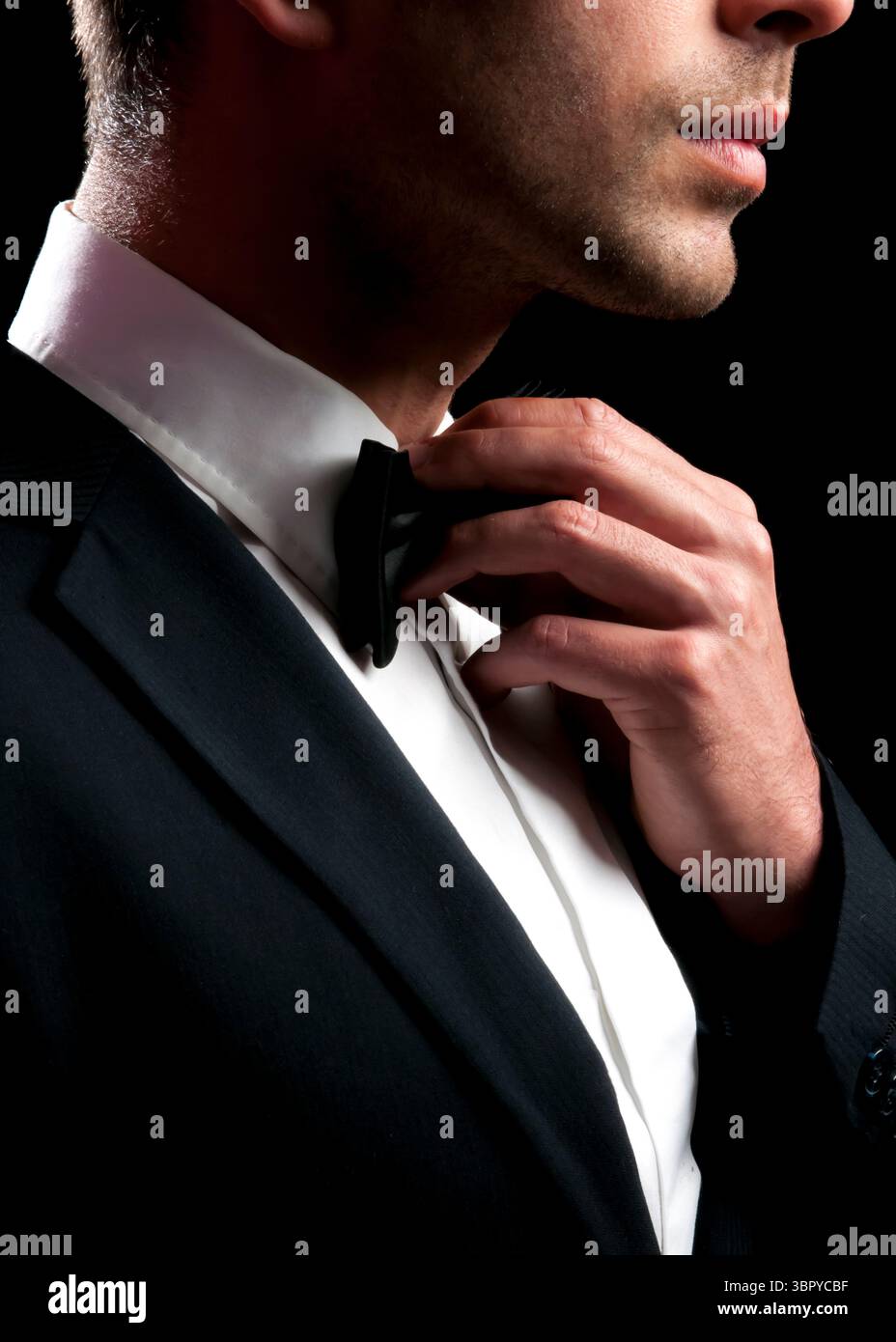 A man in a suit is adjusting his bow tie. Stock Photo