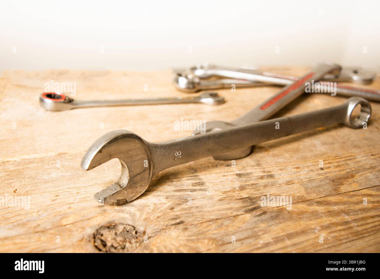 collection of metal wrenches and tools, with an 18mm wrench in foreground focus, arranged on a rustic wooden surface. Stock Photo
