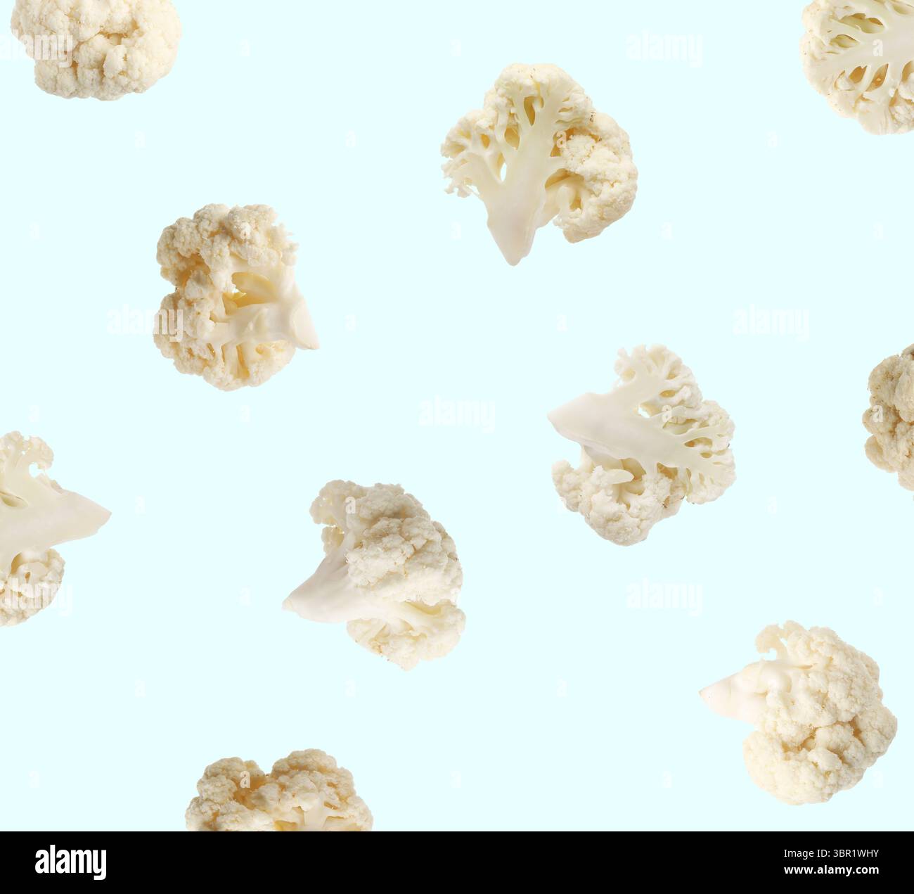 Fresh cauliflower florets falling on light blue background Stock Photo