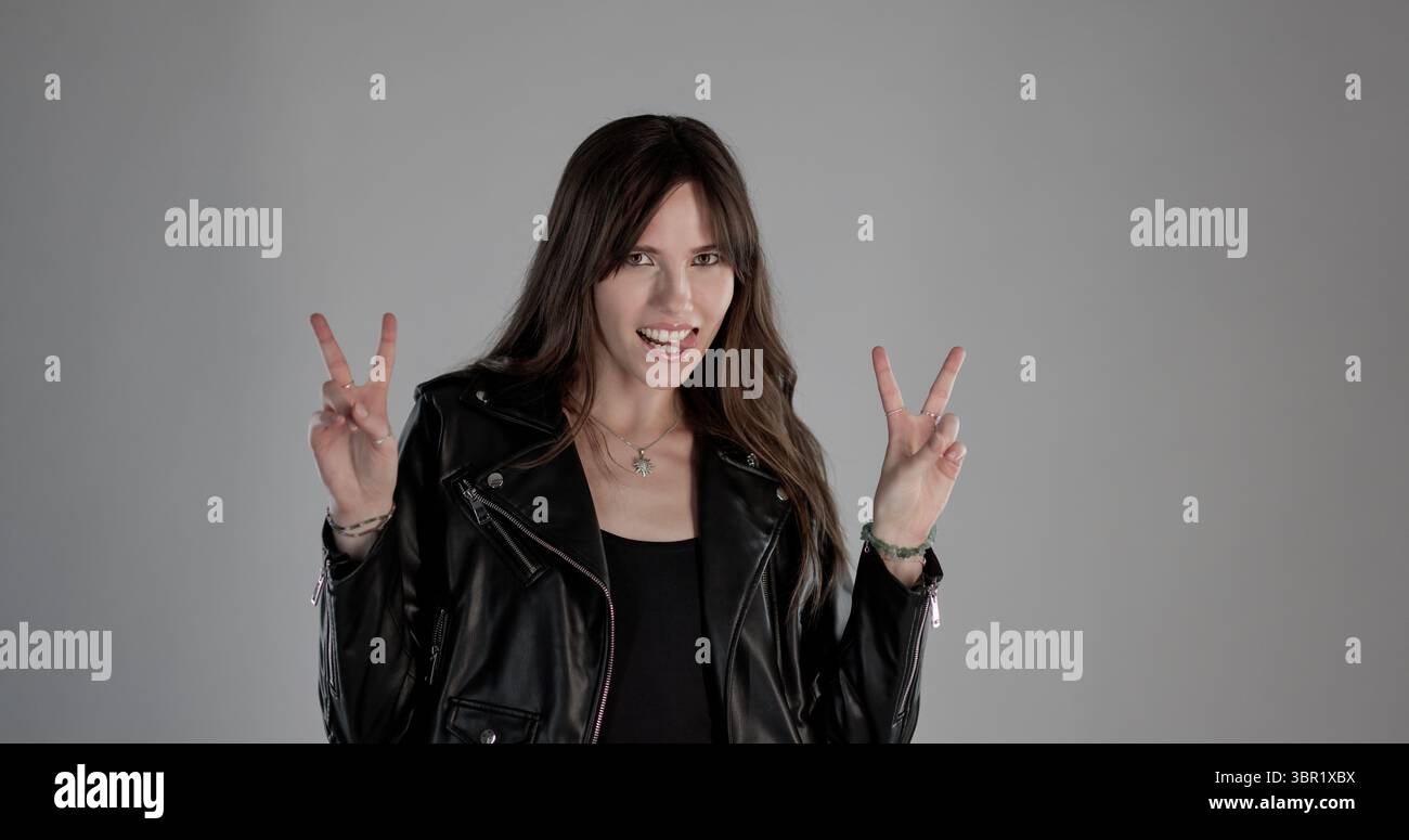 Rocker woman showing peace sign with both hands, sticking out tongue ...