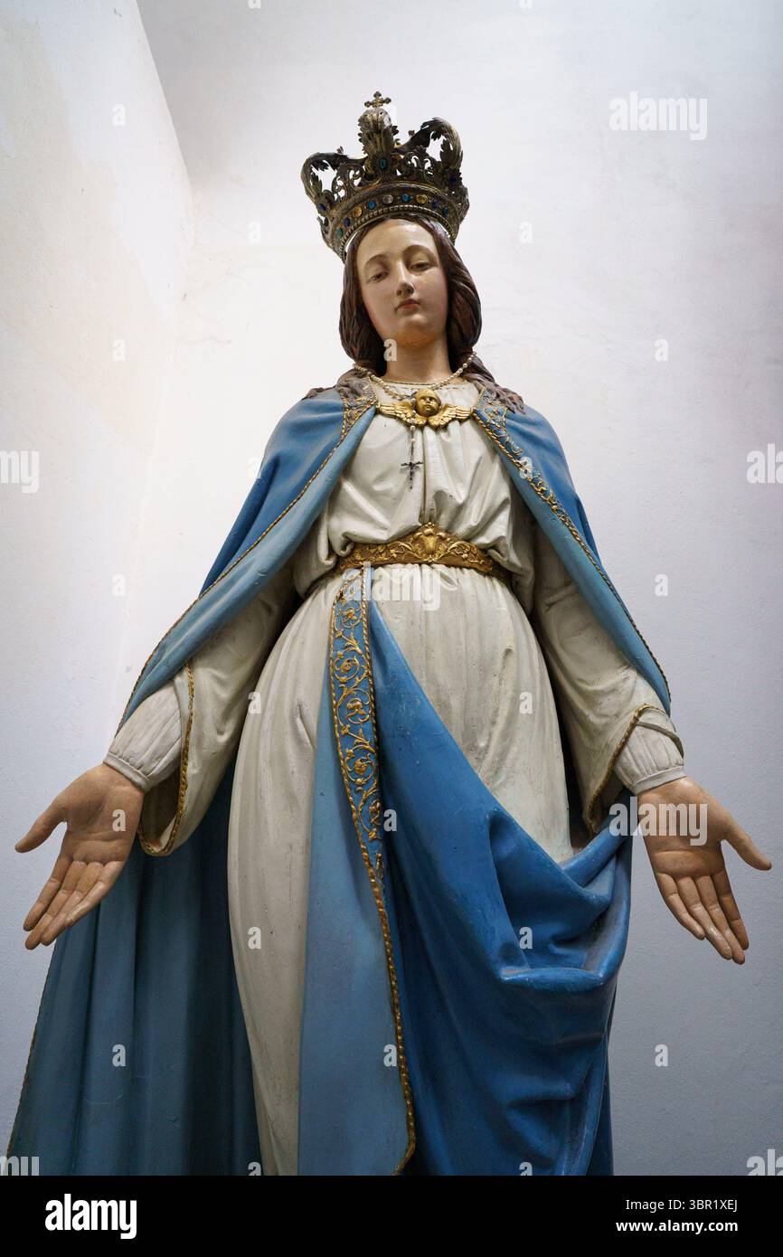 A close-up of a statue of the Virgin Mary, adorned with a golden crown ...