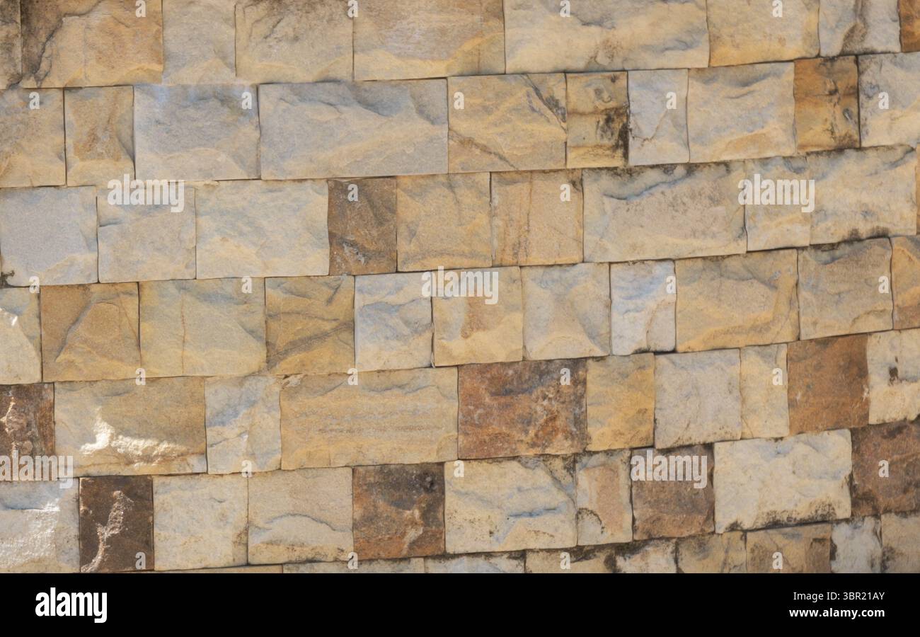 Close-up texture of stacked stone wall blocks in outdoor setting. Stock Photo