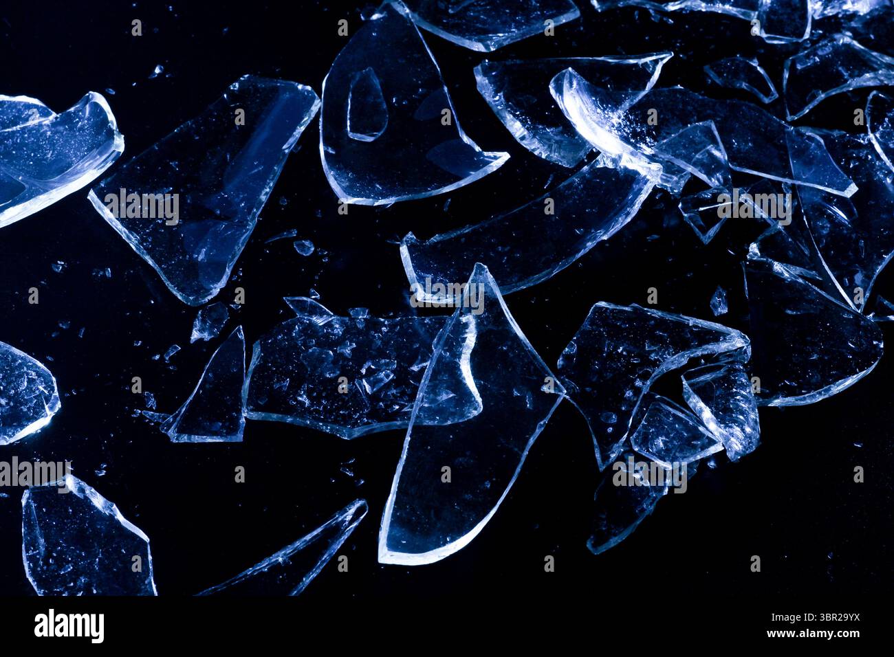 Broken Glass Shards on Dark Surface with Cold Lighting Stock Photo
