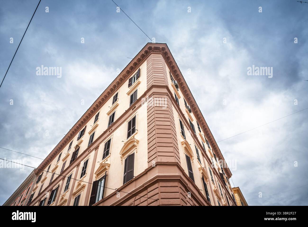 Low angle view of a late 19th-century residential building in central Rome, italy, in old rome, its tall shuttered windows and corner rising against a Stock Photo