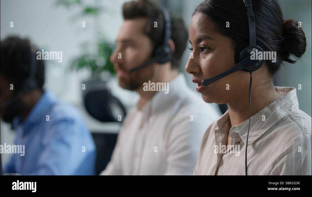 Close up smiling multiethnic team group operators diverse callcenter workers headset microphone consulting customer online service sales Indian Stock Photo