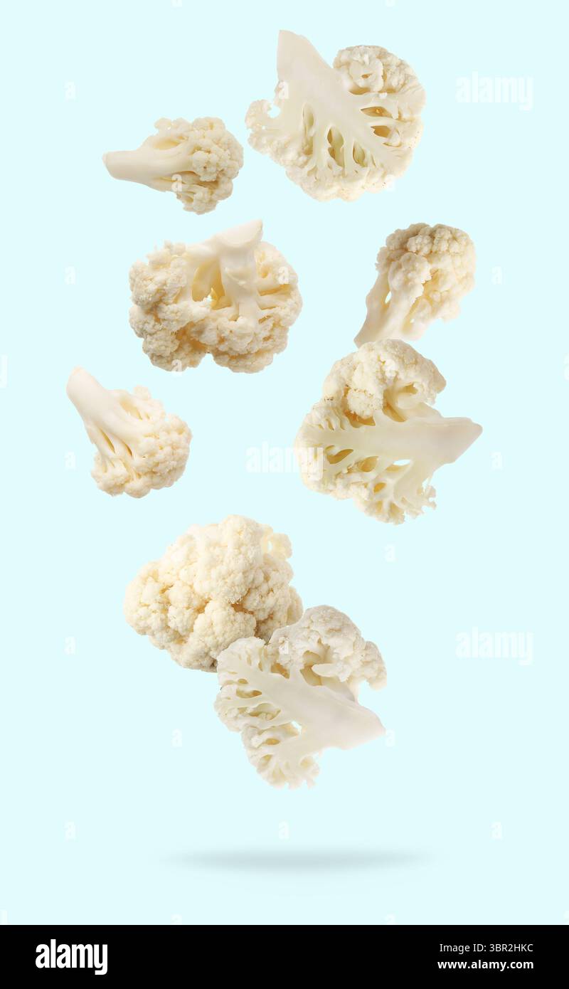 Fresh cauliflower florets falling on light blue background Stock Photo