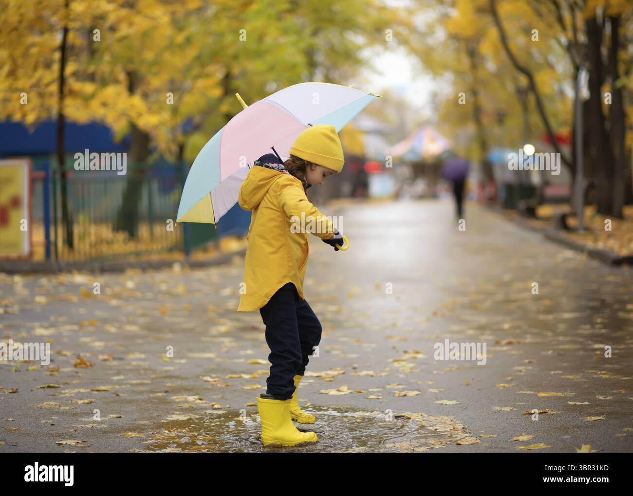 Child in yellow rubber boots and raincoat standing on puddle. Have fun ...