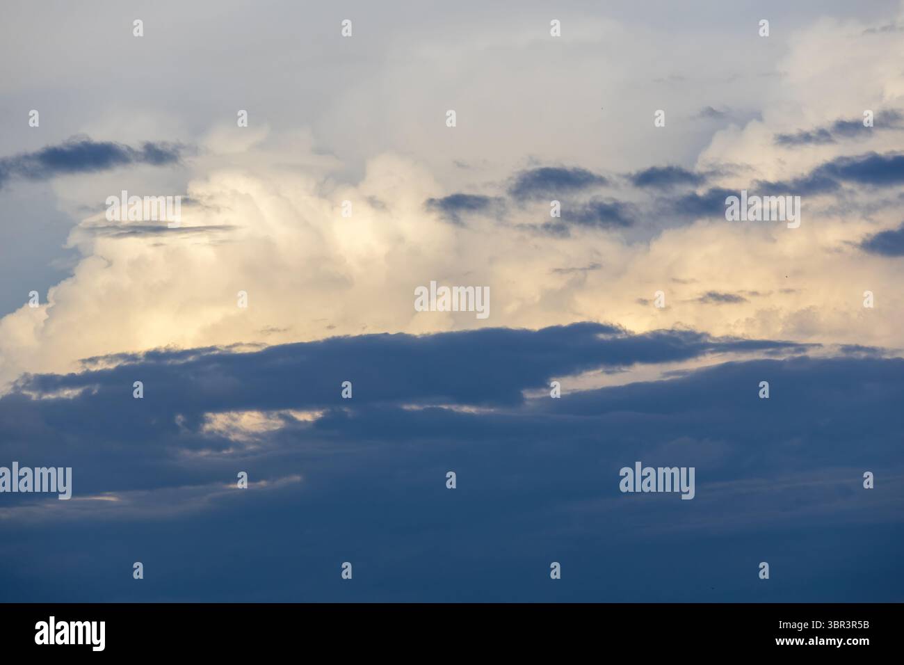 Bluish afternoon sky with dramatic dark and white clouds floating. Capturing the essence of bad weather and stormy atmospheric conditions. Stock Photo