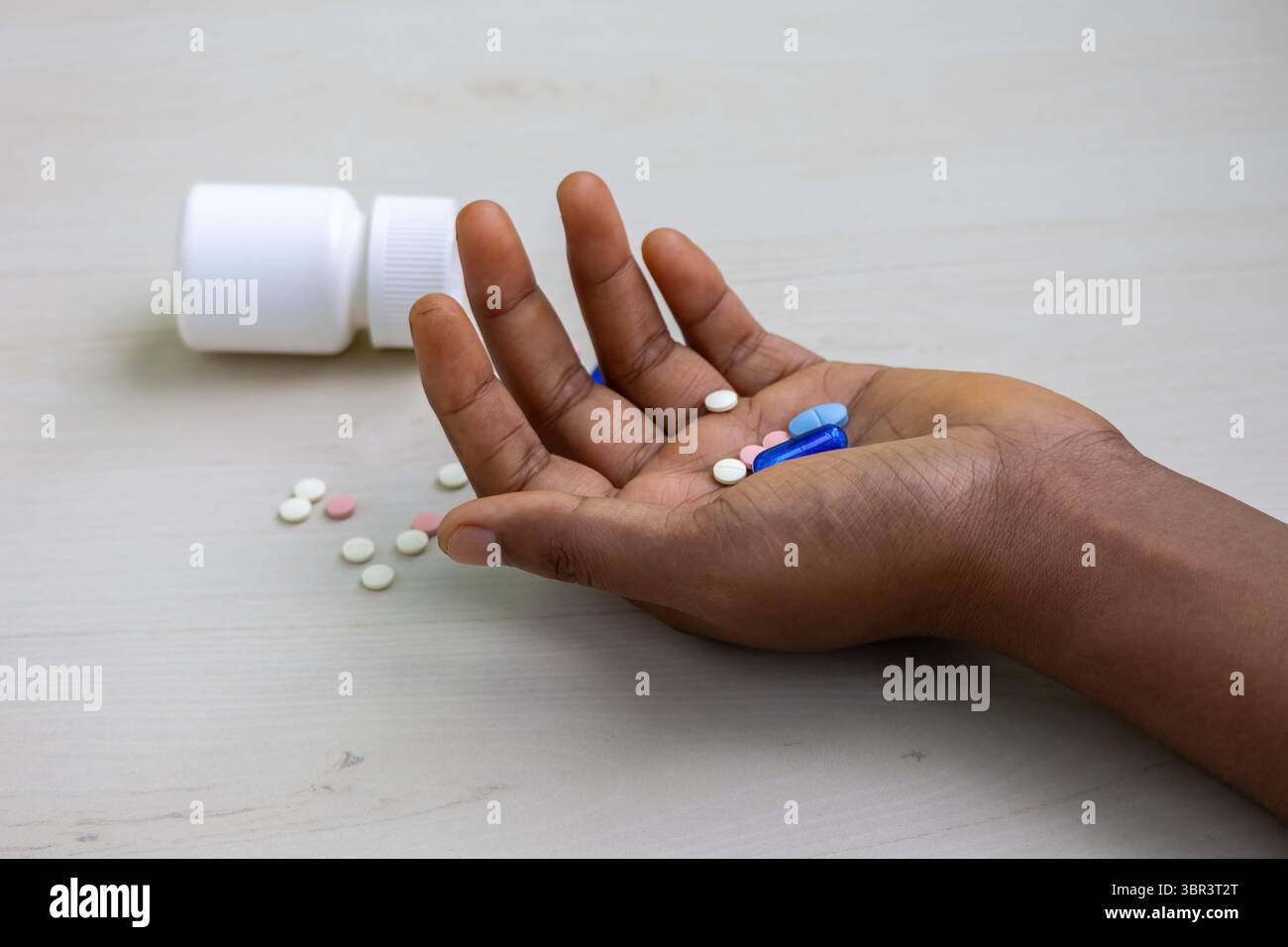 Woman's hand with pills, capsules, and a fallen bottle on the floor ...