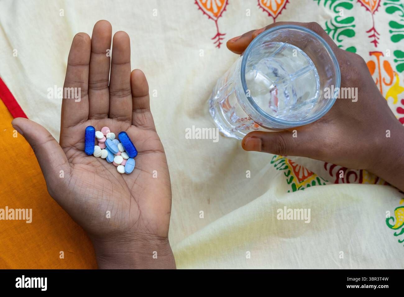 Woman’s hand holds water and medication, including pills and capsules ...