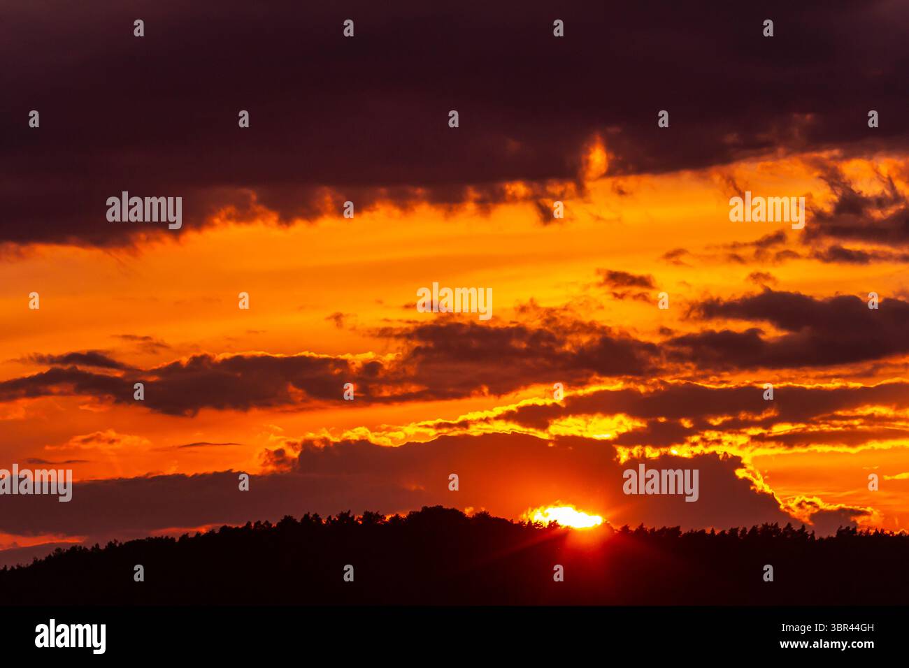Sun dips below the horizon casting warm light across the mountains as ...
