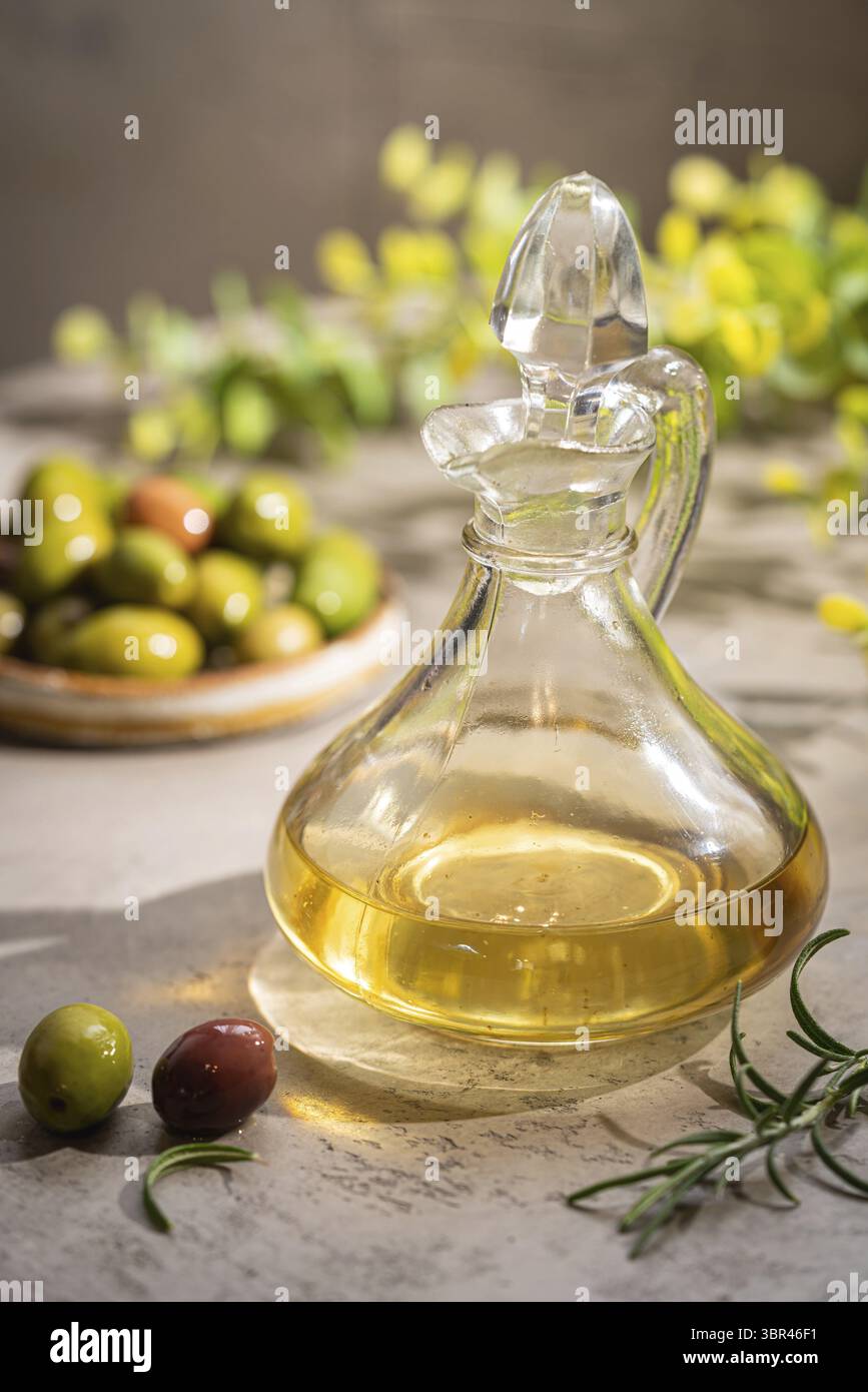 Olive oil in a glass bottle containers and harvest olives with herbs on ...