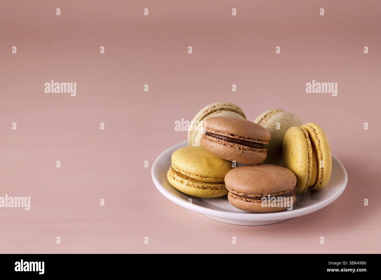 Colored macaroons in a plate on a beige background, copy space Stock Photo