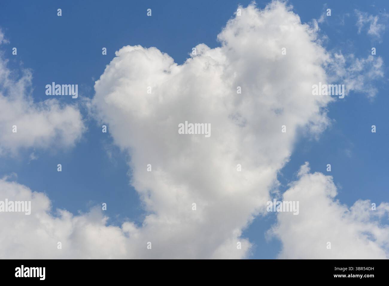 Large white heart shaped cloud on blue sky floating by Stock Photo