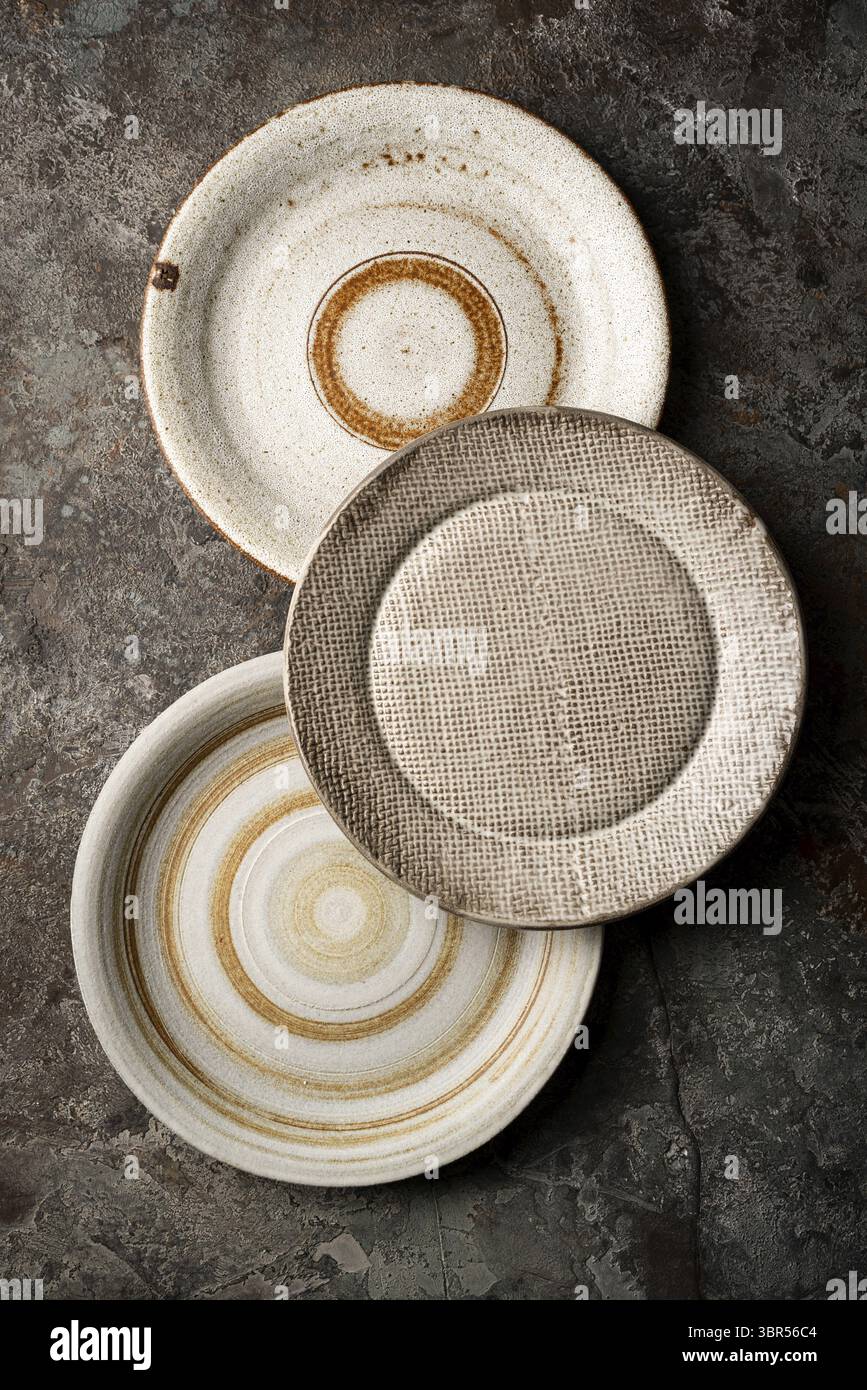 Three different homemade ceramic plates on dark gray background, top view Stock Photo