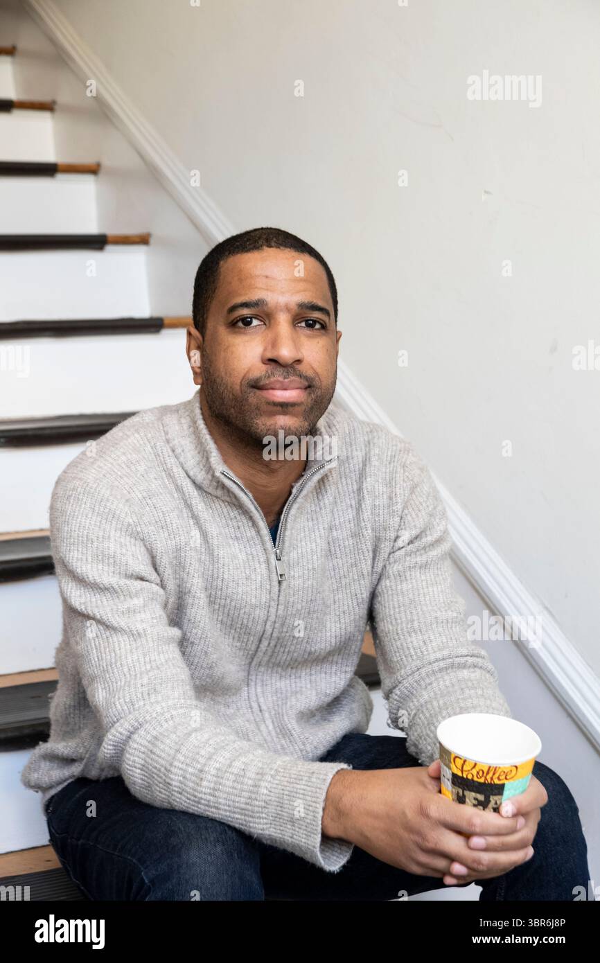 Contemplative man with coffee relaxes on vintage staircase Stock Photo