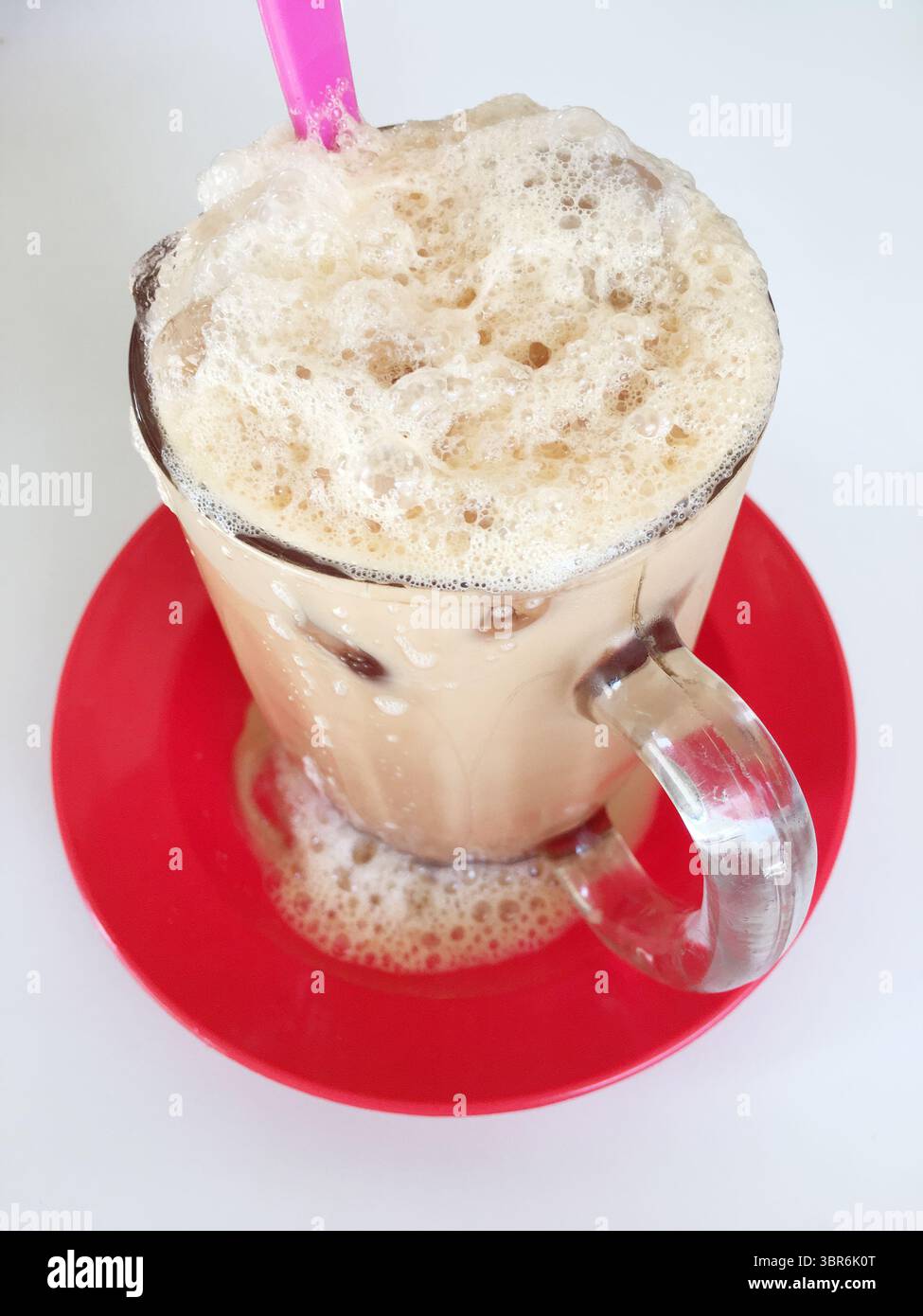 Closeup of a glass of iced teh tarik, a pulled milk tea beverage that ...