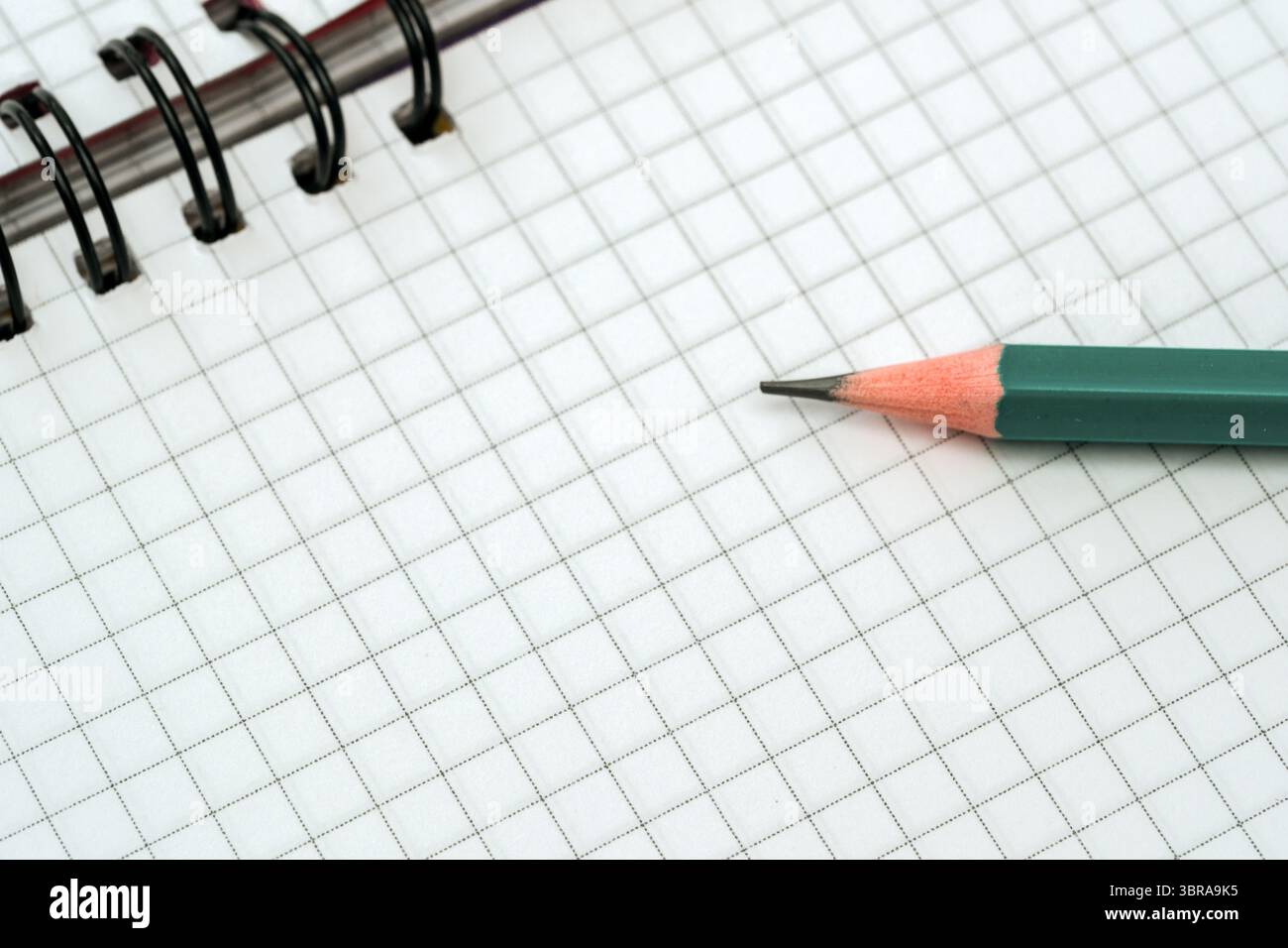 A blank grid notebook lies open beside a sharpened pencil, inviting ideas and sketches. Stock Photo