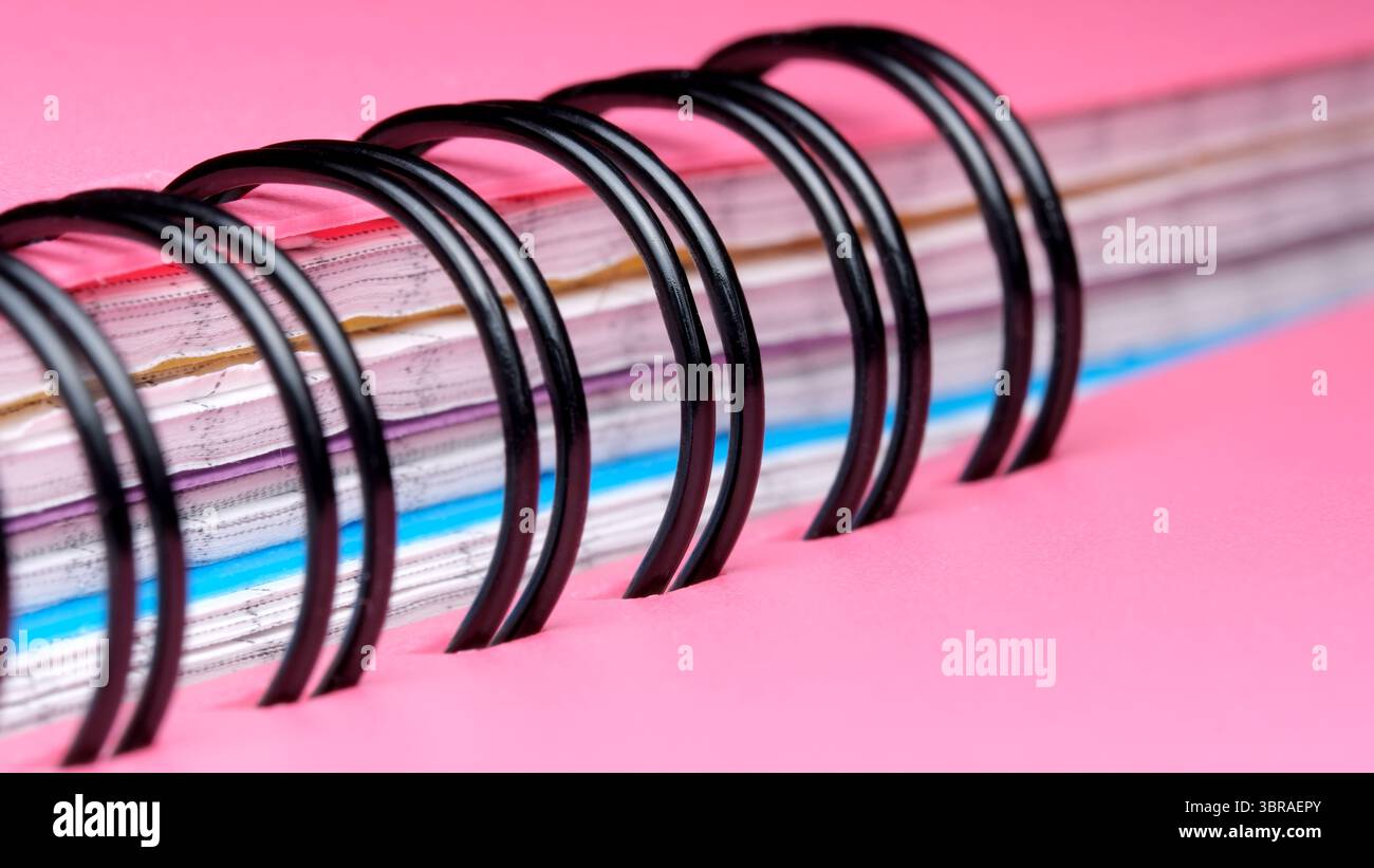 A close-up view of a spiral notebook features vibrant pages and rings. Stock Photo