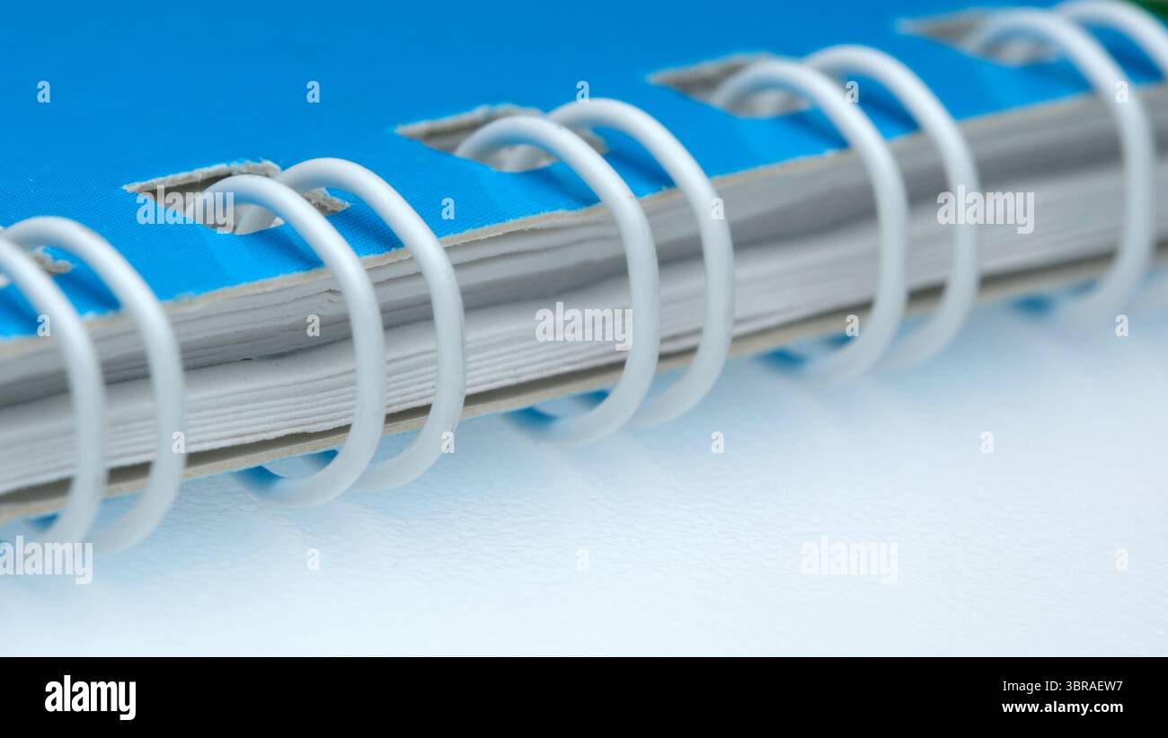 Blue spiral notebook lays open on a clean white surface, ready for notes. Stock Photo