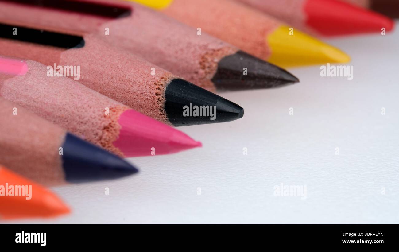 Vibrant colored pencils line up in perfect order on a white surface. Stock Photo
