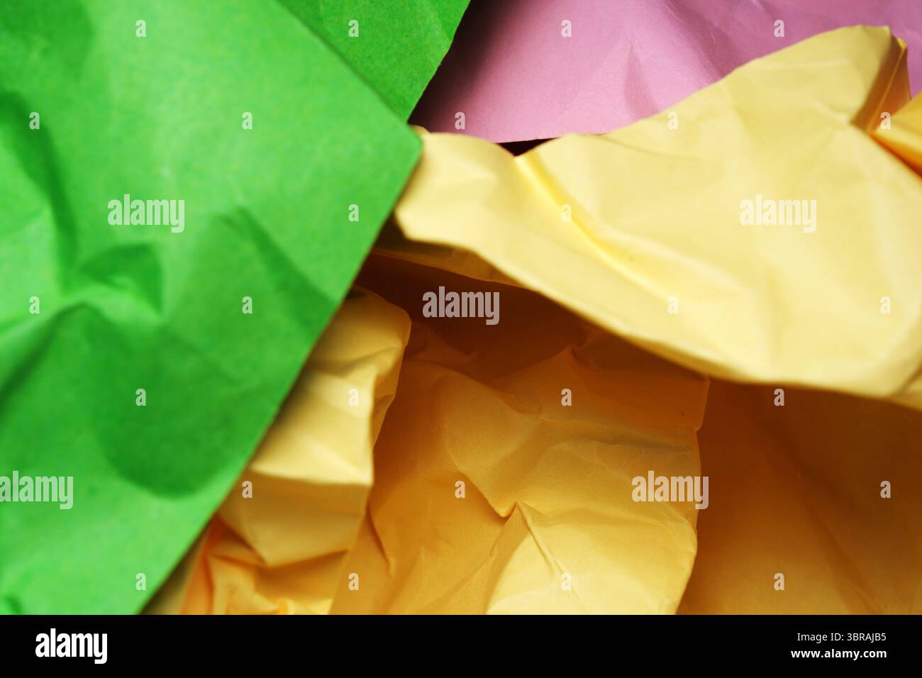 Vibrant sheets of crumpled paper intermingle in a delightful arrangement. Stock Photo