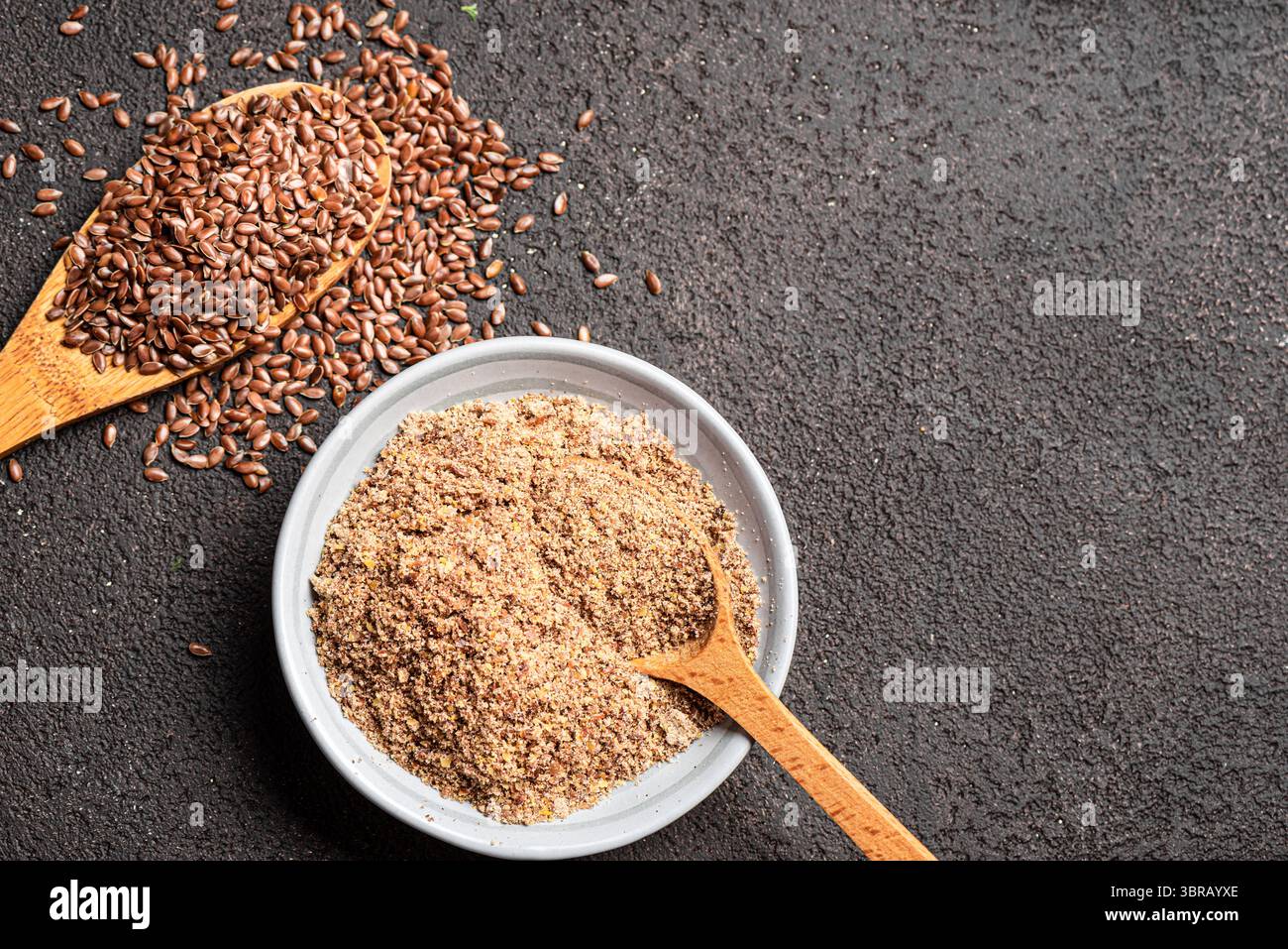 Flaxseeds on wooden spoon and ground of flax seeds, top view, copy