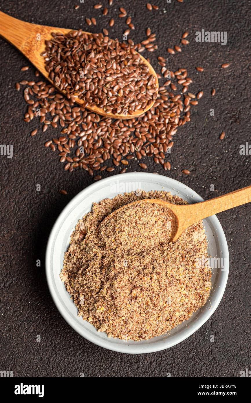 Flaxseeds on wooden spoon and ground of flax seeds, top view. Healthy