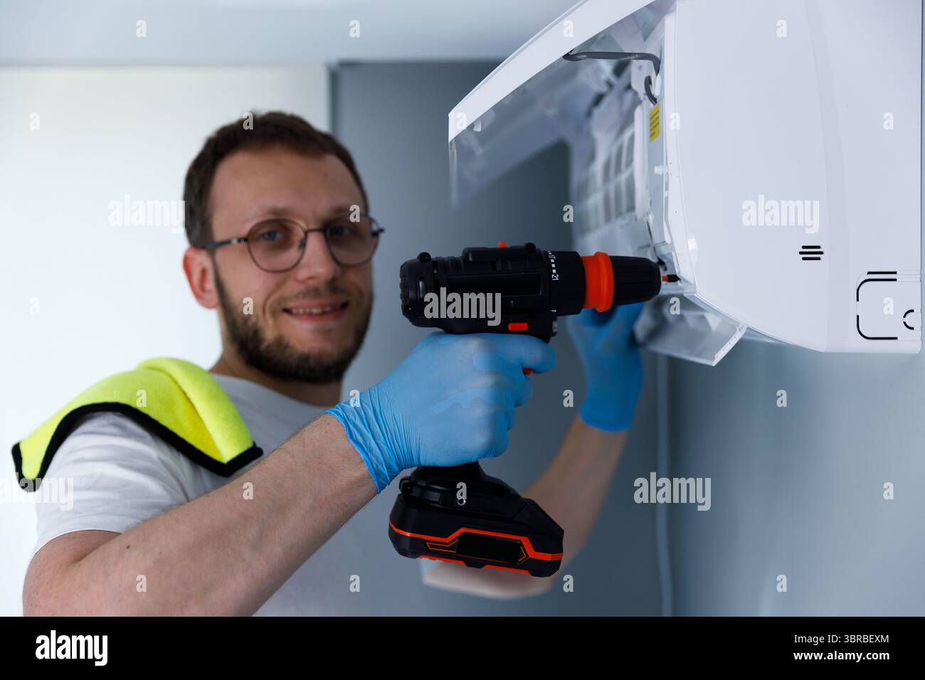 A Skilled Technician Installing an Air Conditioning Unit Using a Cordless Drill, Ensuring Efficient Cooling Solutions for Modern Spaces with Stock Photo