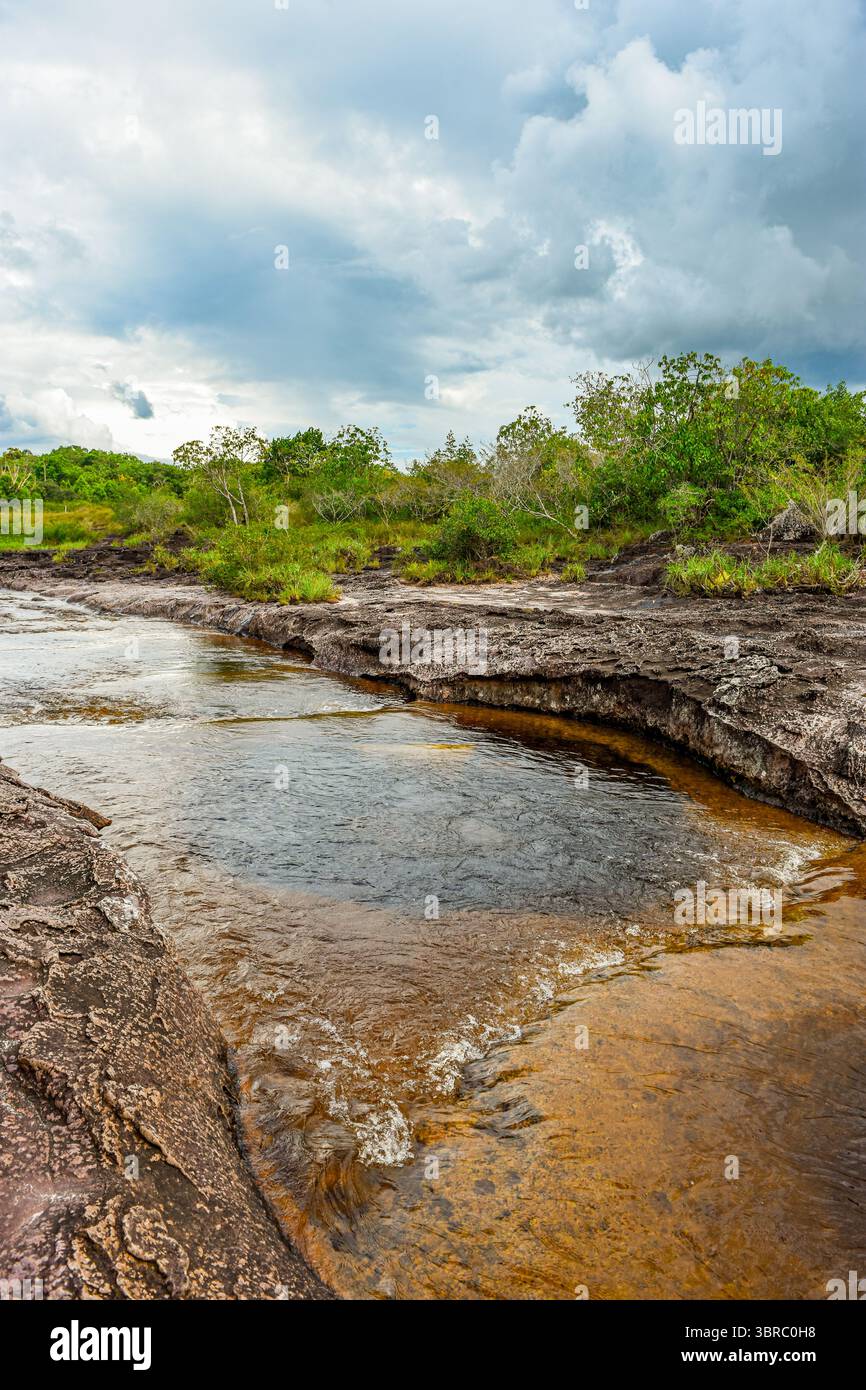 A tranquil river flows through rocky terrain, surrounded by lush ...