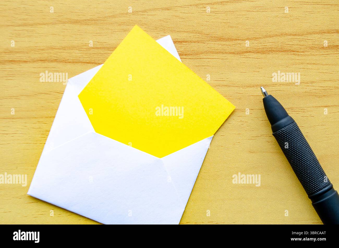Yellow notepad in an envelope on wooden cover background. Customizable ...