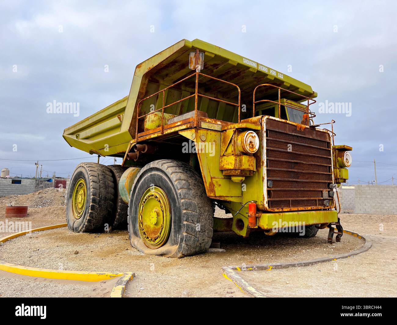 Large old quarry dump truck. Big green rusty mining truck out of work standing for exhibition on the coast of Peru in San Juan de Marcona. Stock Photo