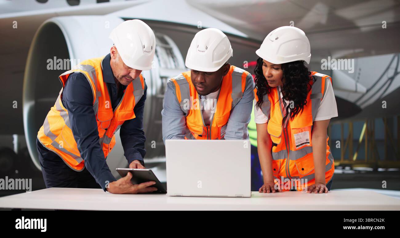 African American Supervisor Inspects Aircraft While Hispanic Technician Repairs Engine. Stock Photo