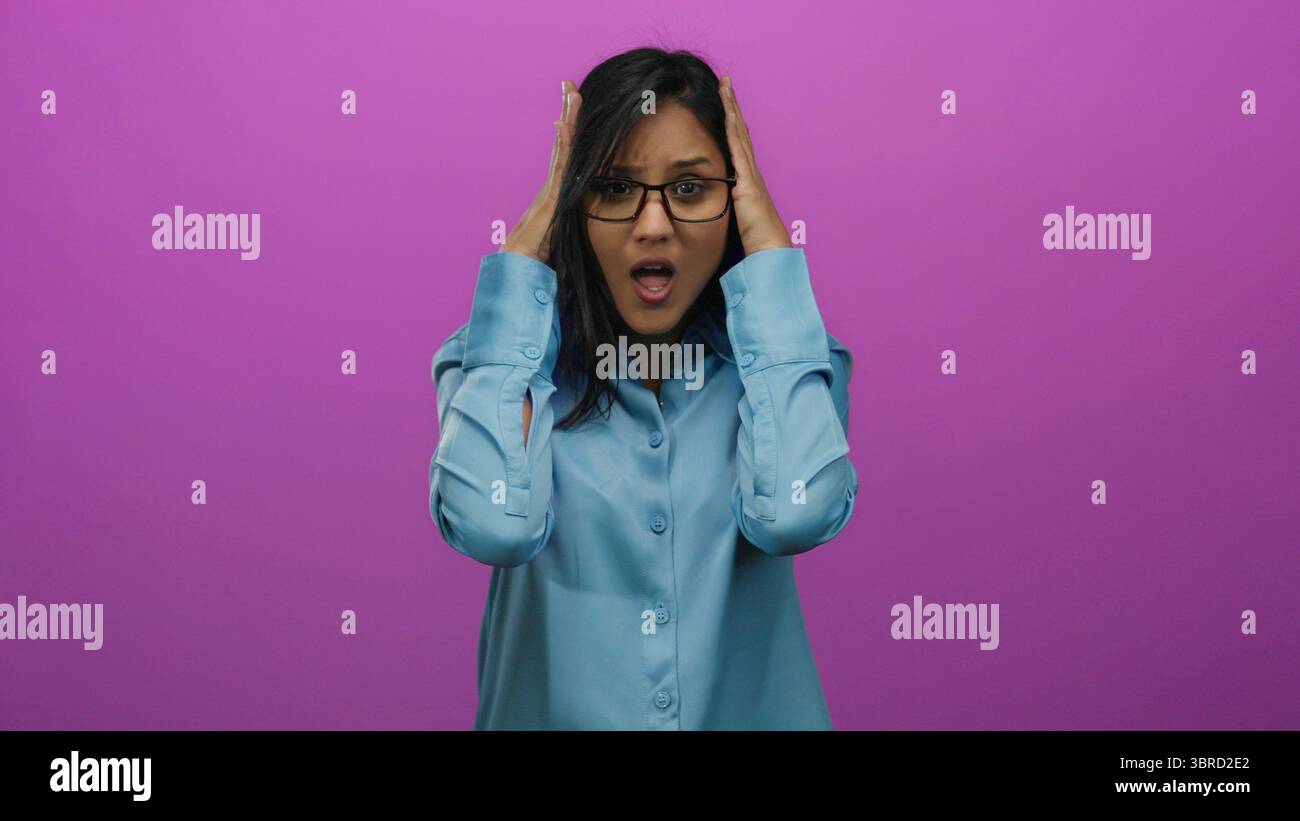 Young hispanic woman in stress holding her head in frustration against an isolated vibrant pink background, expressing overwhelmed emotions. Stock Photo
