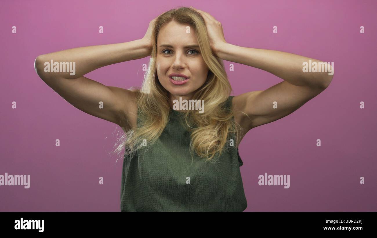 Woman expressing surprise with hands on head against a vivid pink background highlighting emotions and expressions Stock Photo
