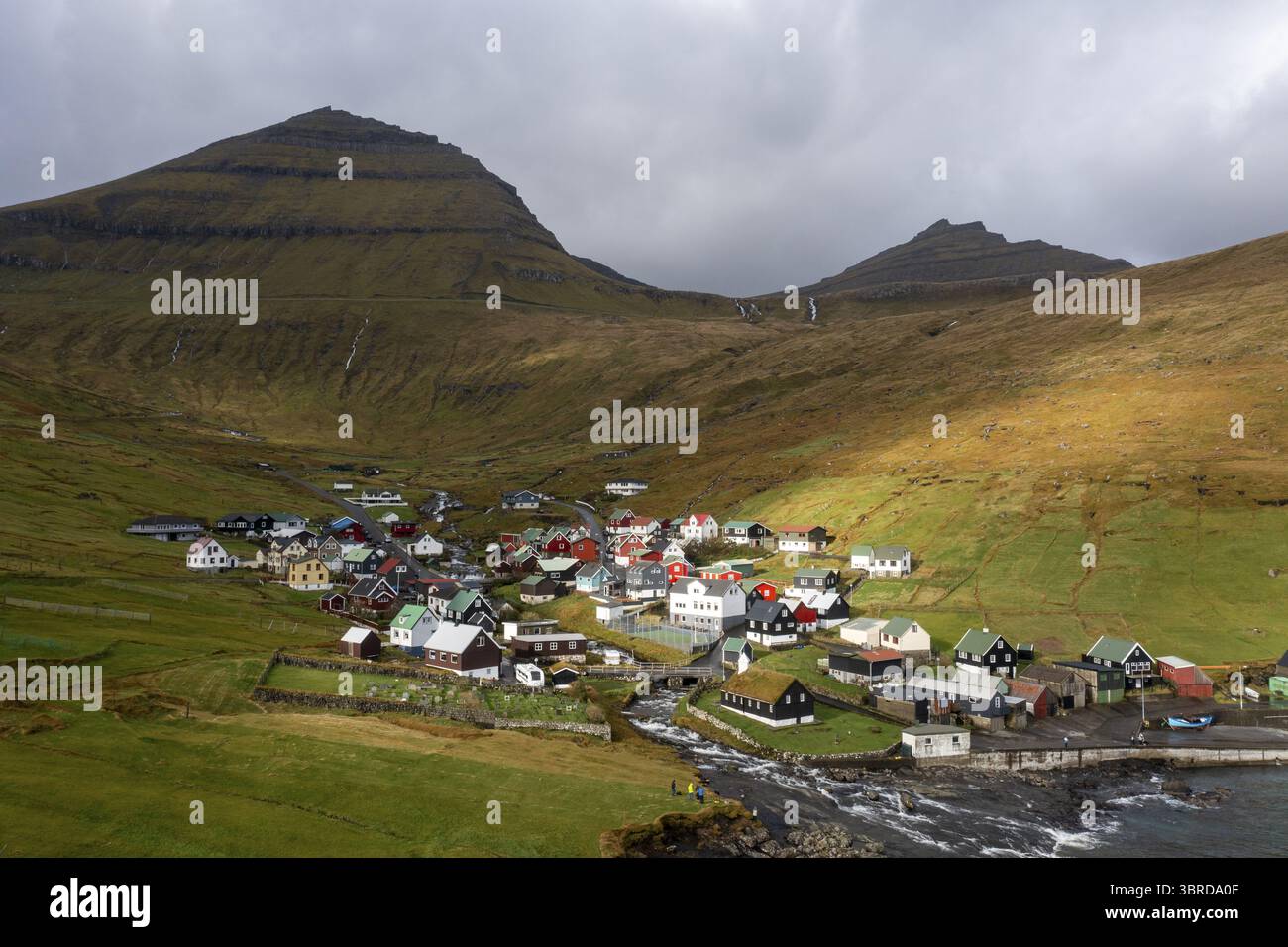 Aerial view of a quaint village nestled between rolling green hills and ...