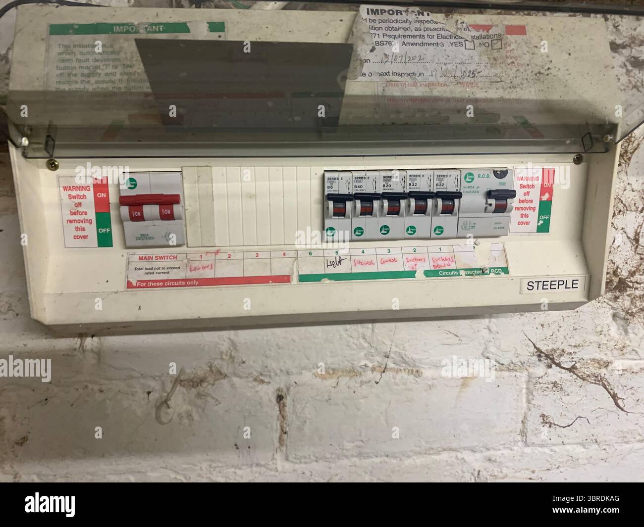Old electrical wiring mains unit gas box pipes wires cables dirty dingy fitted to the wall in a cellar meter gas electricity wood frame electrical  UK - Smartphone Captured Stock Image