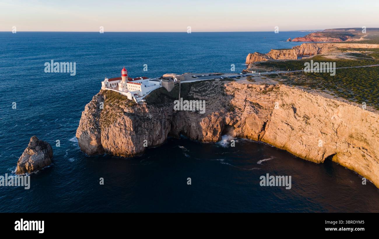 Aerial view of the stark white lighthouse atop the rugged, sun-kissed ...