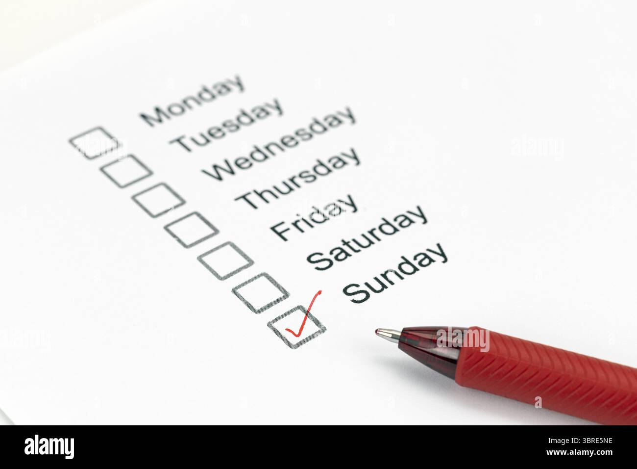 A checklist of weekdays with sunday marked by red pen, indicating completion or importance. list includes monday through sunday Stock Photo