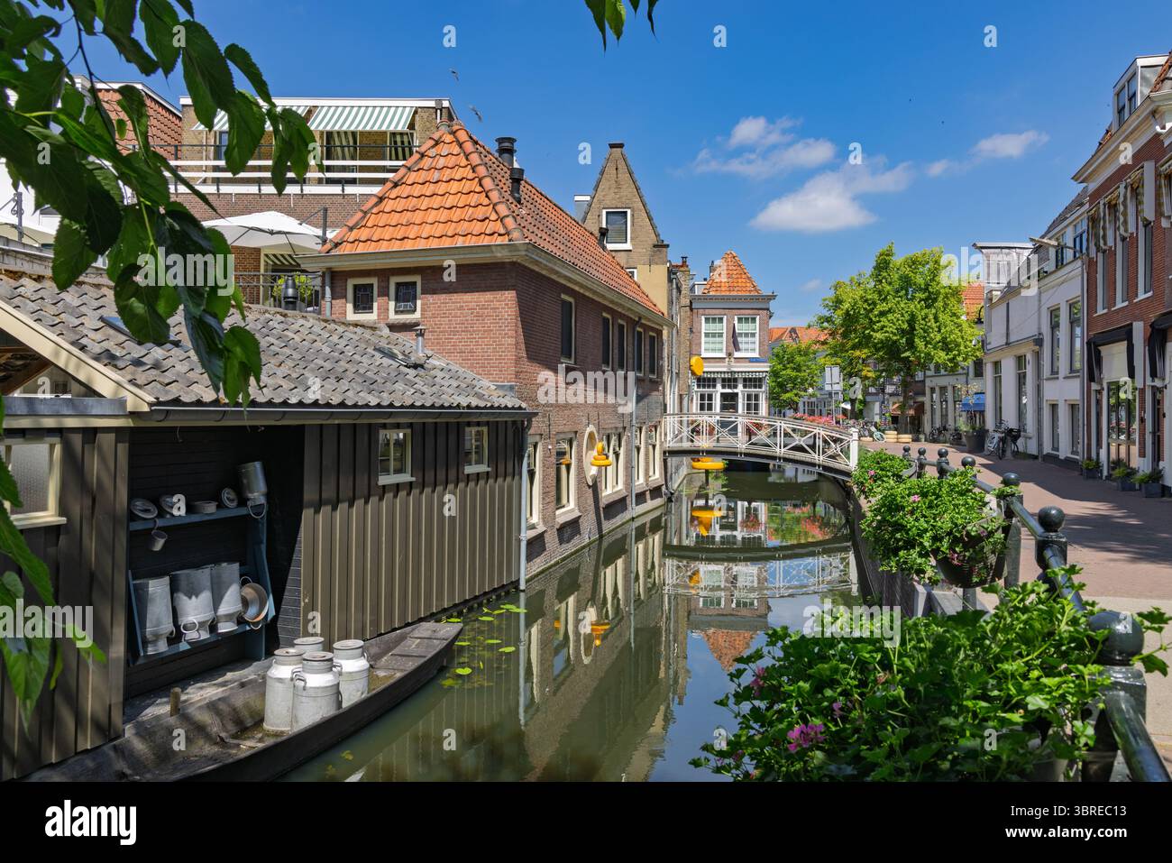 Charming Dutch canal scene with traditional houses, and the Cheese shop Gouda, a quaint bridge, and lush greenery, embodying picturesque European city Stock Photo