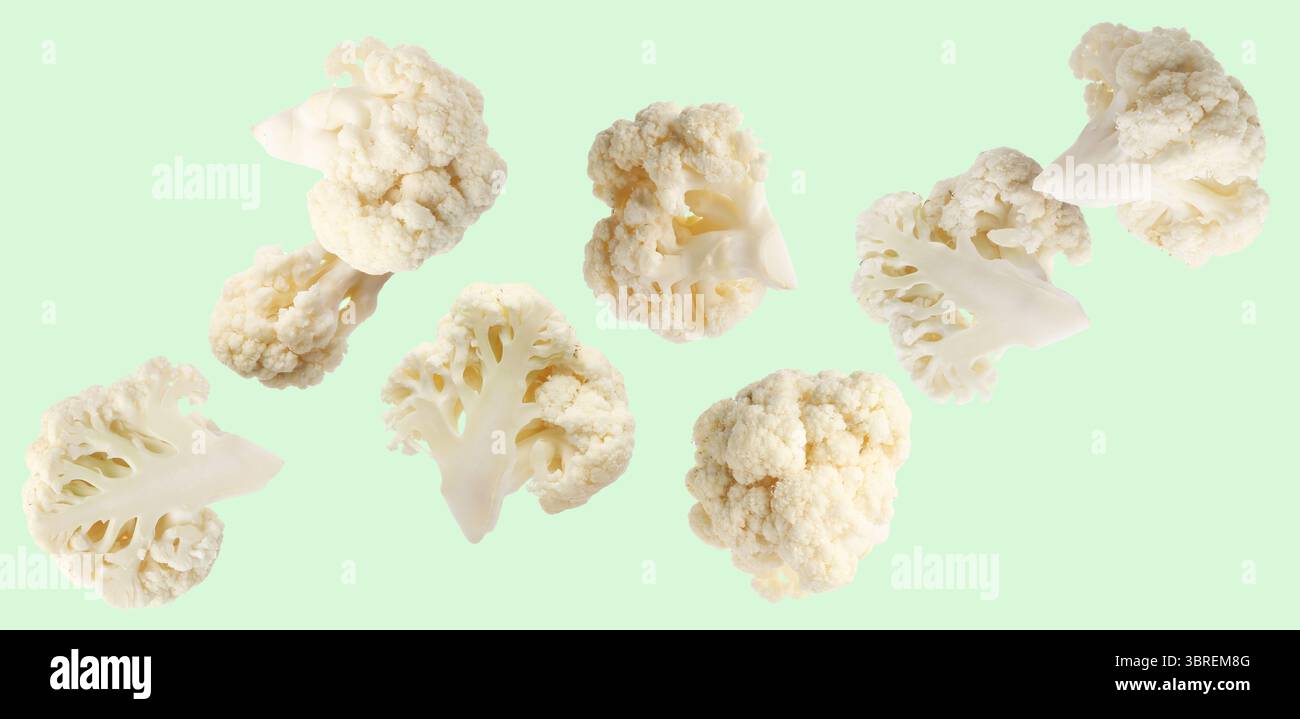 Fresh cauliflower florets falling on light green background Stock Photo