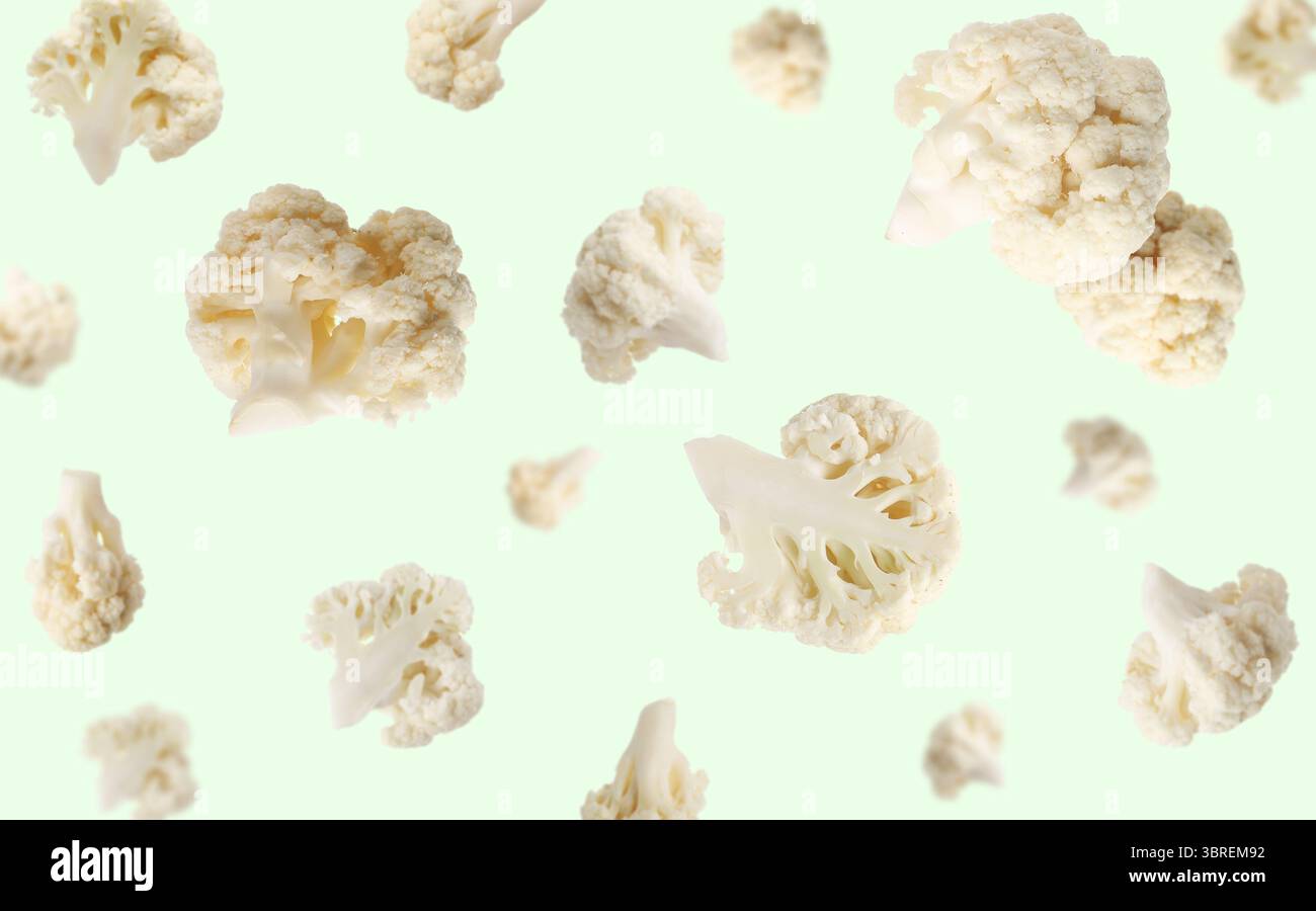 Fresh cauliflower florets falling on light green background Stock Photo
