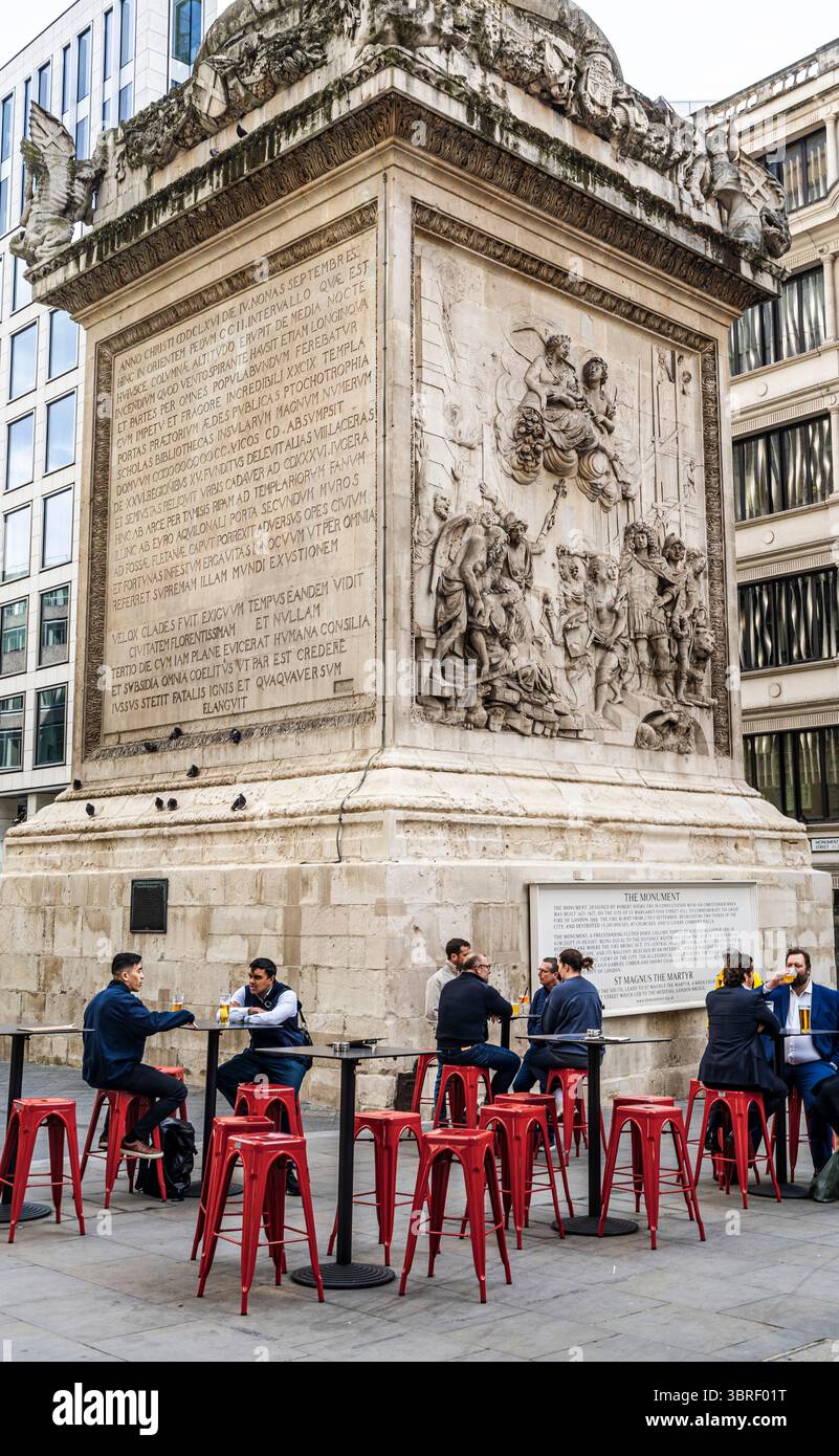 People drinking and relaxing under the Monument to the Great Fire of London, Doric column in the historic City of London, United Kingdom Stock Photo