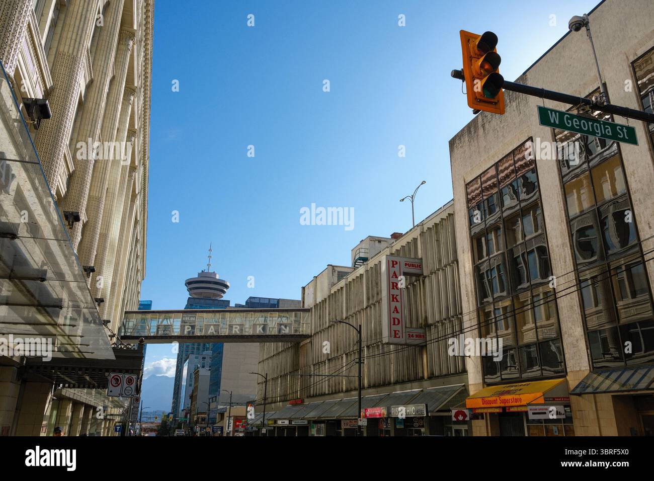A pedestrian overpass connects the Hudson Bay Building to a parkade along Seymour Street with the Vancouver Lookout building behind. Stock Photo