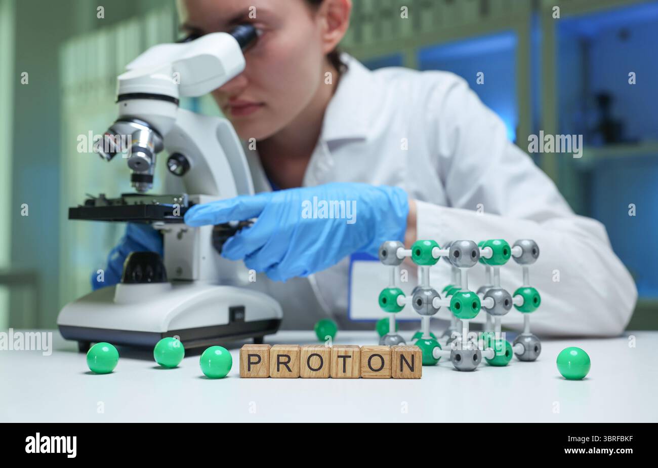 Proton Through Microscope A scientist observing protons through a microscope in a lab for ...