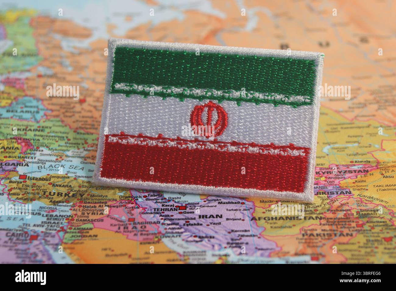 Iranian flag made from fabric, placed on a world map highlighting Iran’s location. A concept of national pride, travel, and environmental awareness. Stock Photo