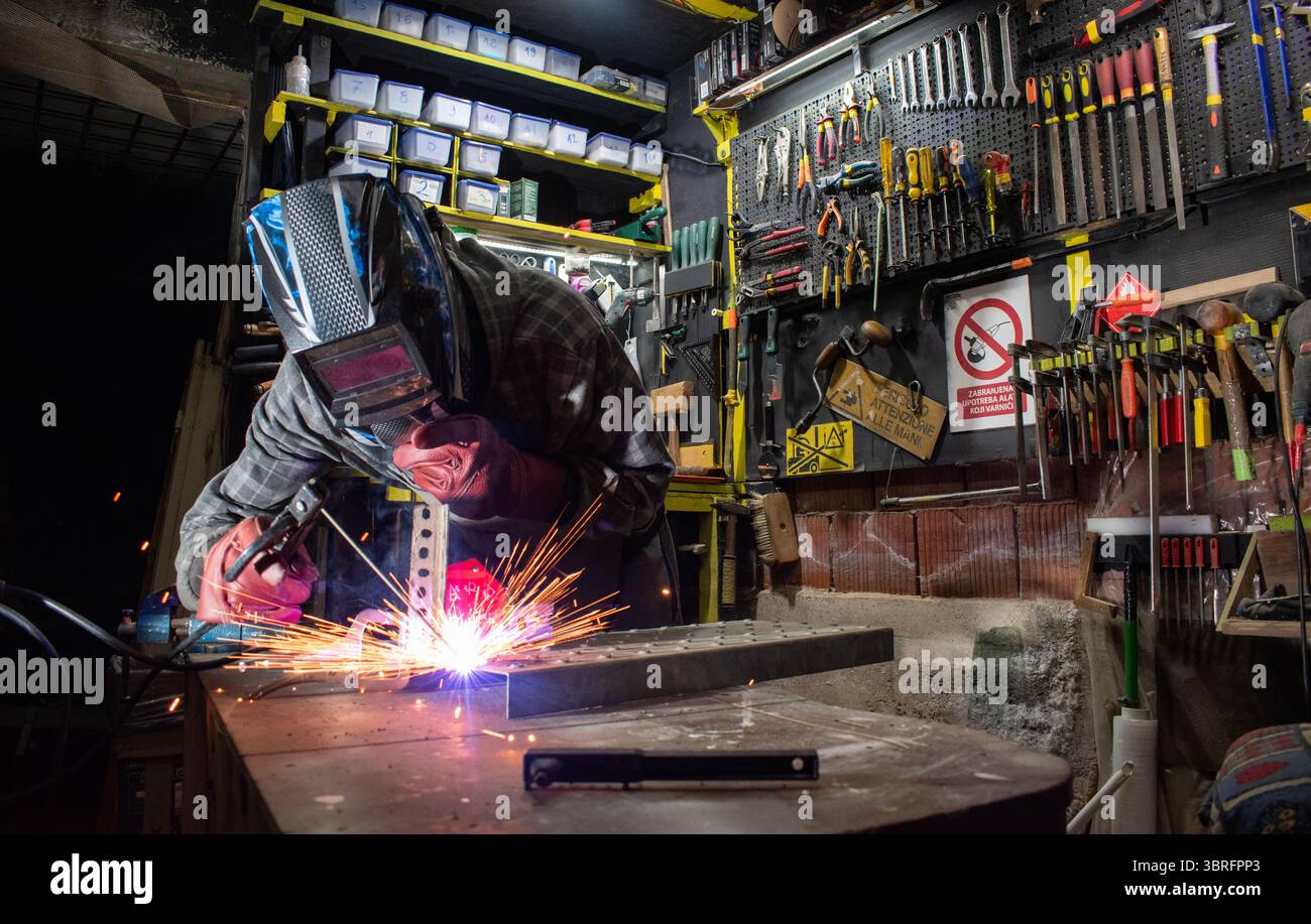 Worker with protective mask welding metal in workshop Stock Photo