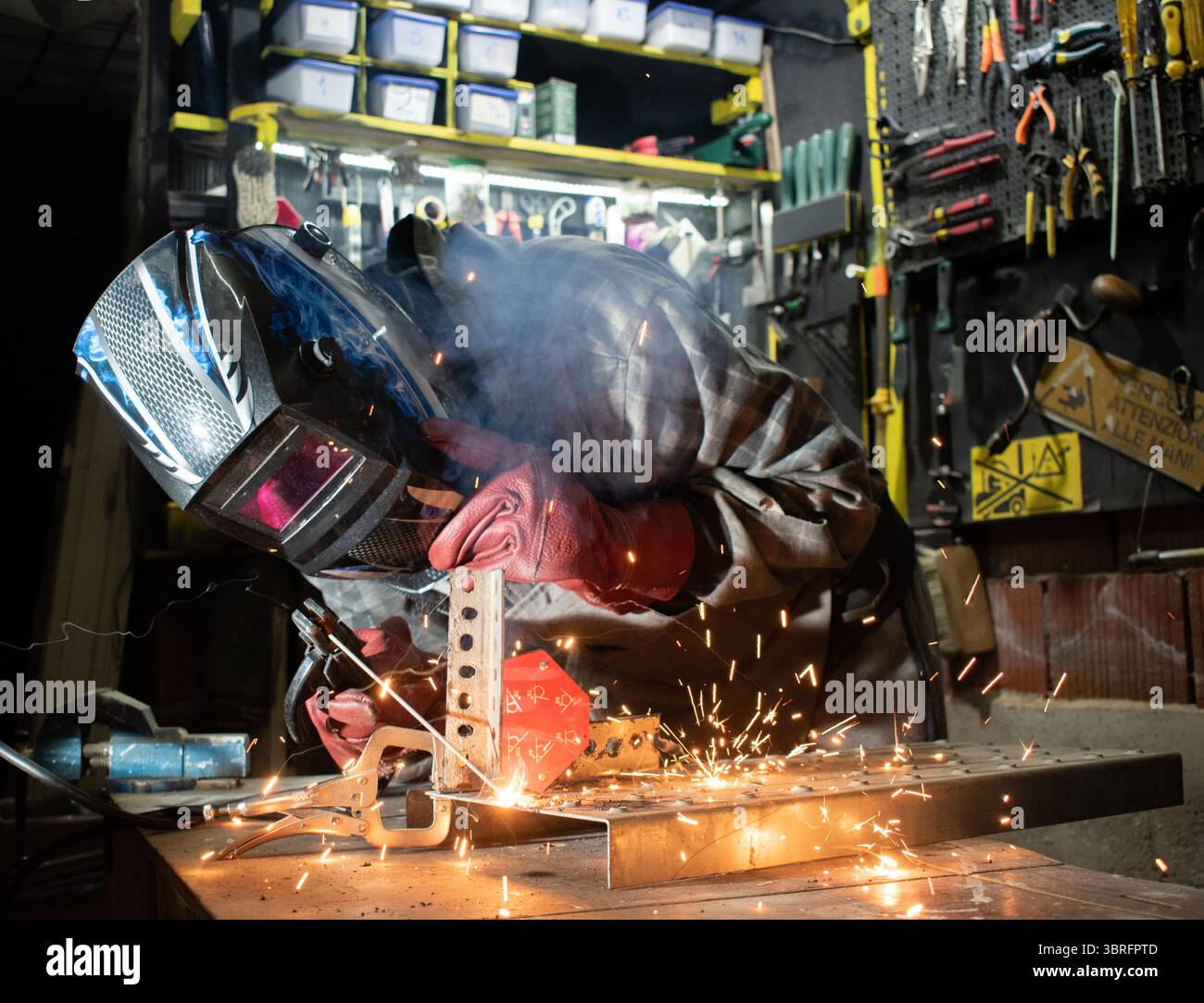 Worker with protective mask welding metal in workshop Stock Photo