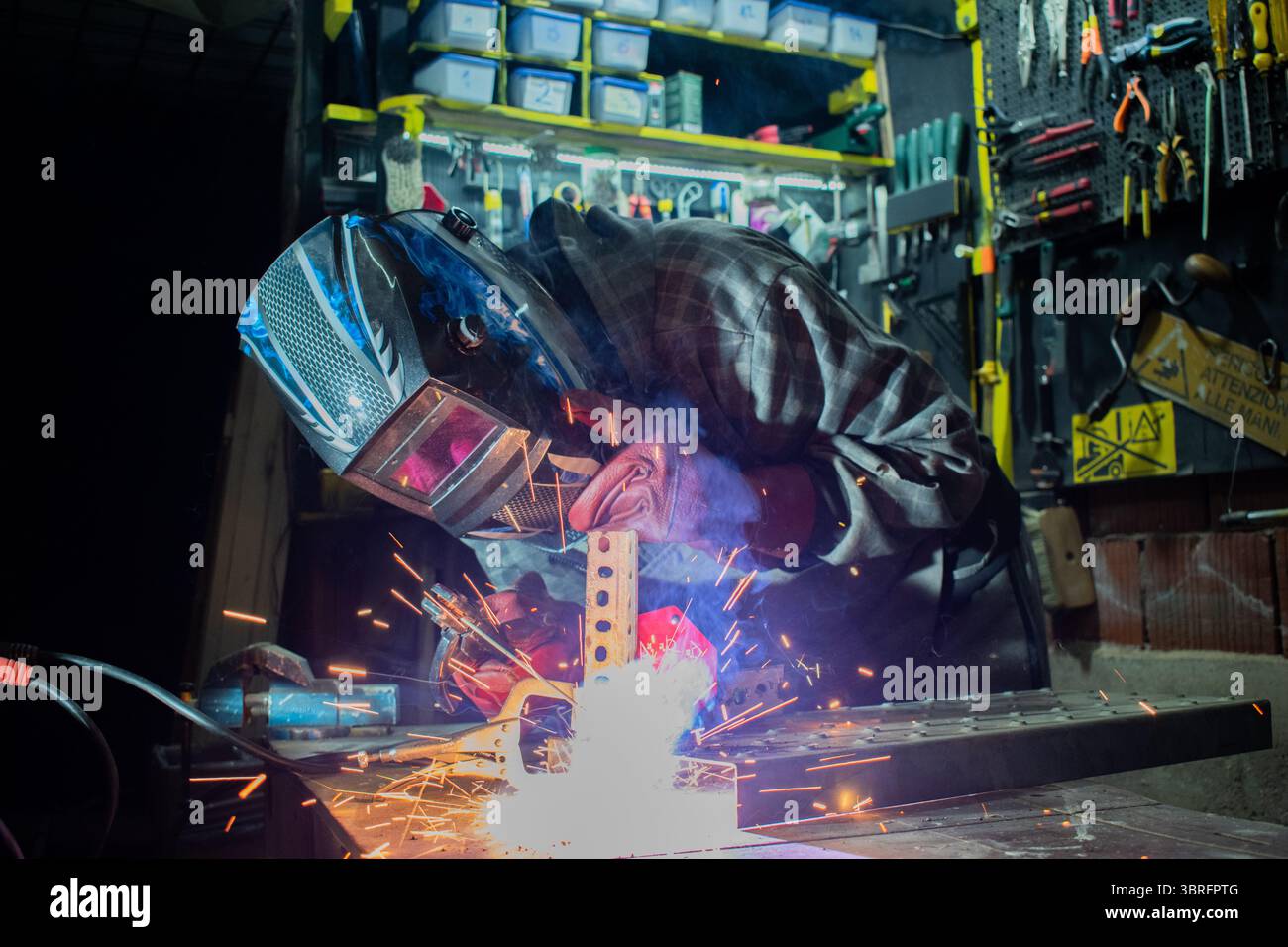 Worker with protective mask welding metal in workshop Stock Photo