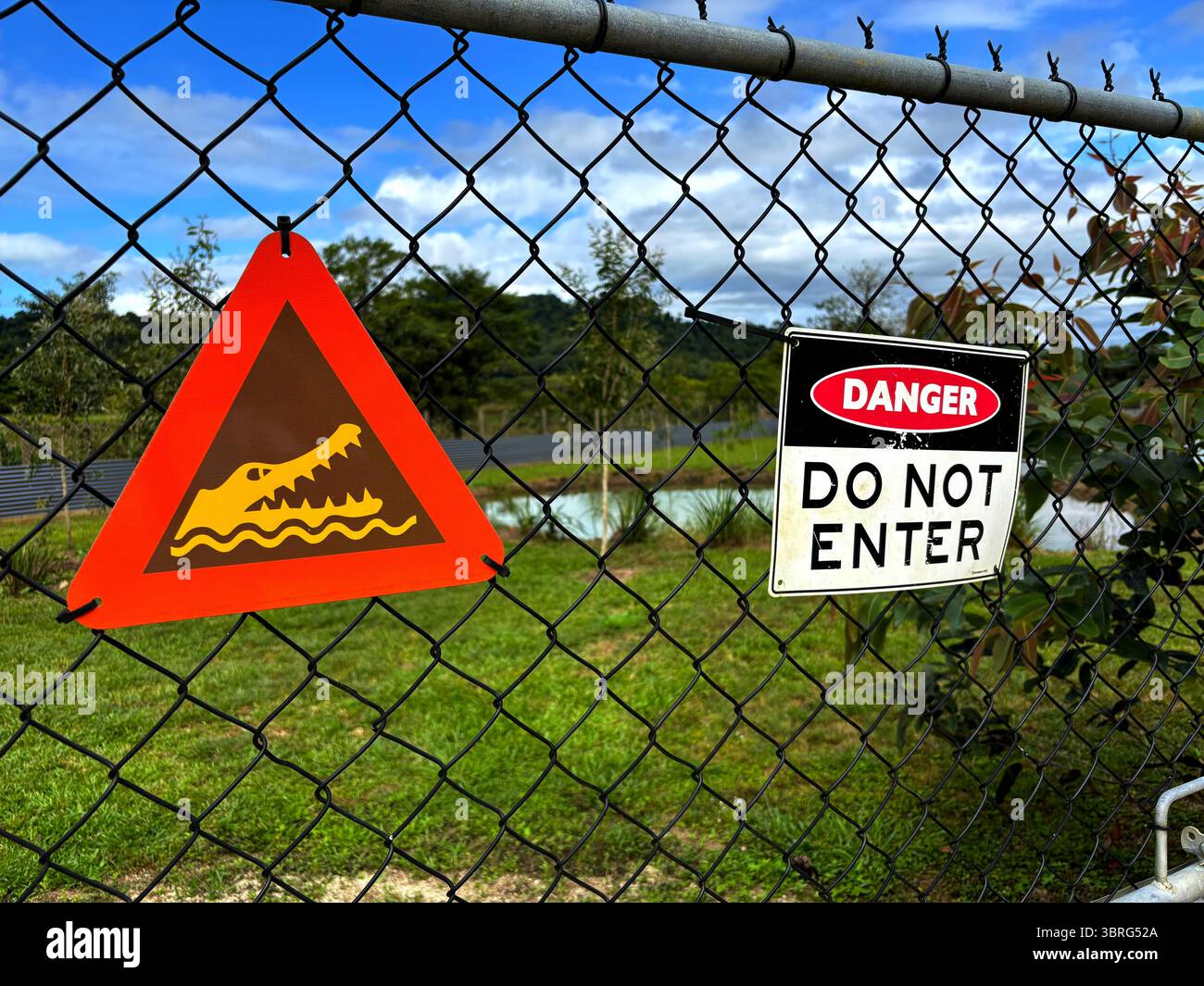 Warning signs on fence around crocodile holding pond, East Russell, near Babinda, Cairns, Queensland, Australia. No PR - Smartphone Captured Stock Image